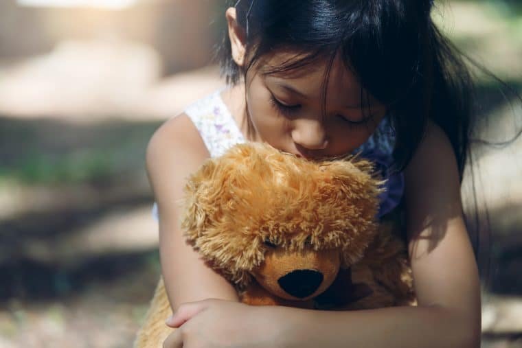 sad young girl hugging teddy bear