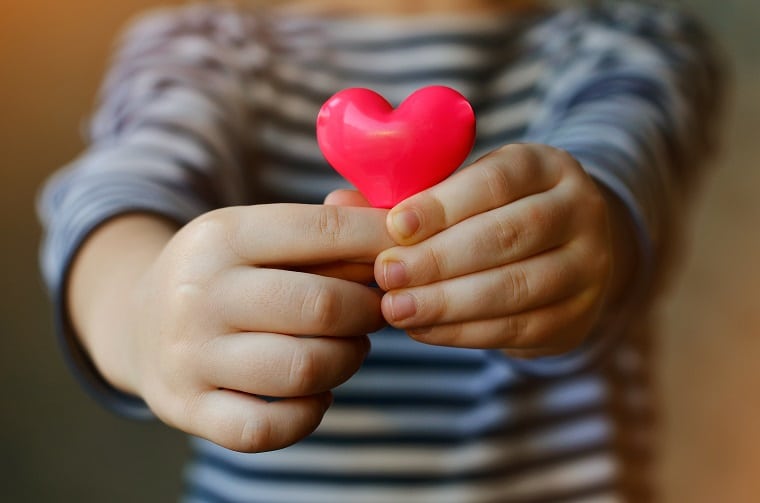 child holding a small pink heart
